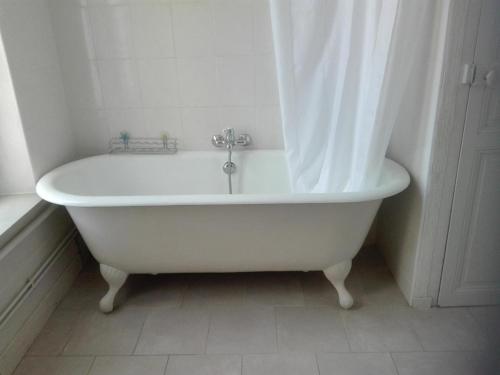 uma banheira branca com uma cortina de chuveiro na casa de banho em Gîte Gipcy, 6 pièces, 10 personnes - FR-1-489-504 