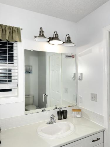 een witte badkamer met een wastafel en een spiegel bij K E vacation house in Nanaimo