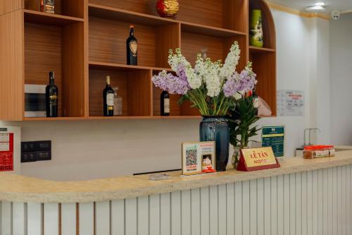 eine Vase Blumen auf einer Theke mit Weinflaschen in der Unterkunft Trung Huyền Hotel in Sa Pa