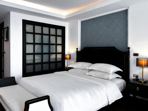 a bedroom with a large white bed and a window at Glory Boutique Suites 清迈古城荣耀精品酒店 in Chiang Mai