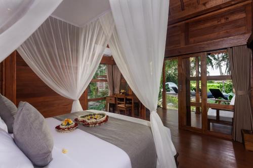 1 dormitorio con 1 cama con cortinas blancas en Berlima Wooden Lodge by Pramana Villas, en Ubud