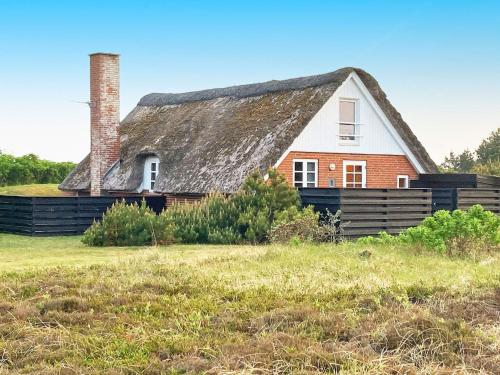 een oud huis met een rieten dak op een veld bij 6 person holiday home in Ringk bing in Ringkøbing