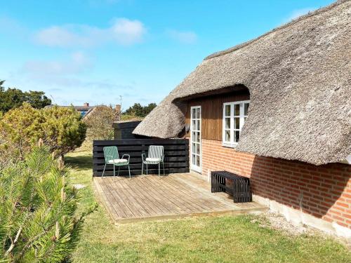 a thatch roofed house with two chairs and a deck at 6 person holiday home in Ringk bing in Ringkøbing