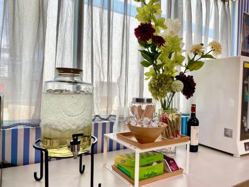 a table with a jar of water and flowers on it at Loju Seaview Homestay in Xiaoliuqiu