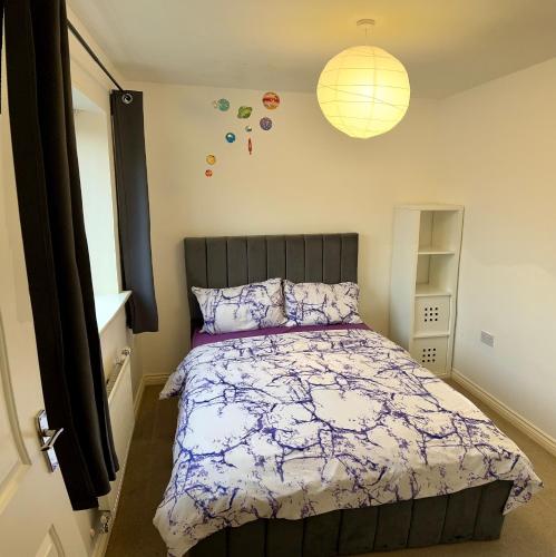ein Schlafzimmer mit einem Bett mit einer lila und weißen Bettdecke in der Unterkunft Comfortable double room with shared spaces in West Bromwich