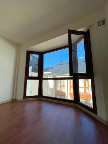 ein leeres Wohnzimmer mit großen Fenstern und Holzböden in der Unterkunft Terrazas del Sur in San Carlos de Bariloche