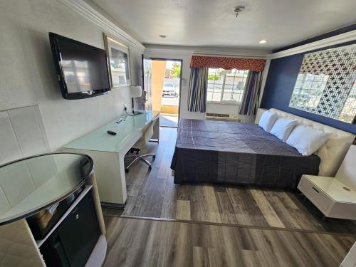 羅斯密的住宿－火烈鳥酒店，一间卧室配有一张床、一张书桌和一台电视。