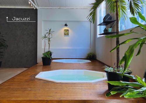 um quarto com uma banheira de hidromassagem num piso de madeira com plantas em Kastel Grão Pará em Petrópolis