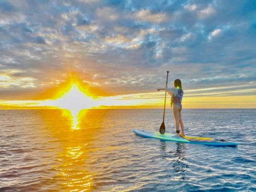 a woman is standing on a paddle board in the water at Oceanic Pearl Resort in Xiaoliuqiu