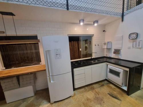 Il comprend une cuisine équipée d'un réfrigérateur blanc et d'un comptoir. dans l'établissement Casa do Descanso com jacuzzi em Igaratá, à Igaratá