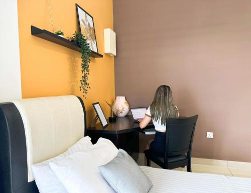 a woman sitting at a desk with a laptop at Manhattan Austin By JC Home in Johor Bahru