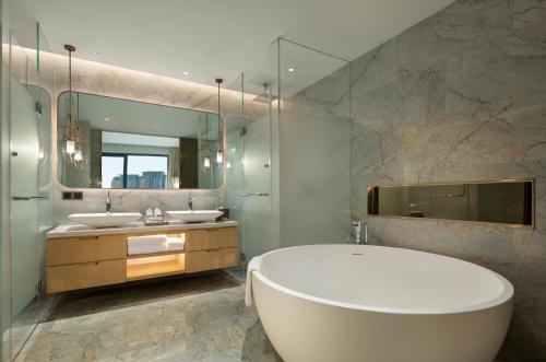 bagno con 2 lavandini, vasca e specchio di Hilton Garden Inn Sanya a Sanya