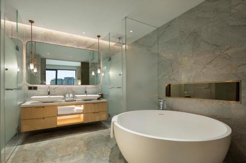 a bathroom with two sinks and a tub and a mirror at Hilton Garden Inn Sanya in Sanya