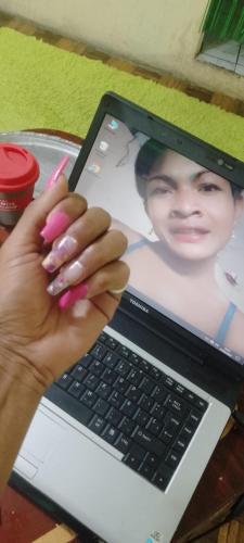 Een vrouw met roze nagellak en een laptop. bij Nails spa niño robert in Quito