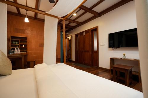 a bedroom with a bed and a flat screen tv at Little Chembaka in Kumarakom