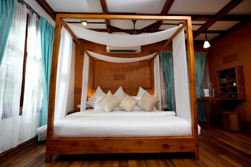 a bedroom with a canopy bed with white sheets and pillows at Little Chembaka in Kumarakom