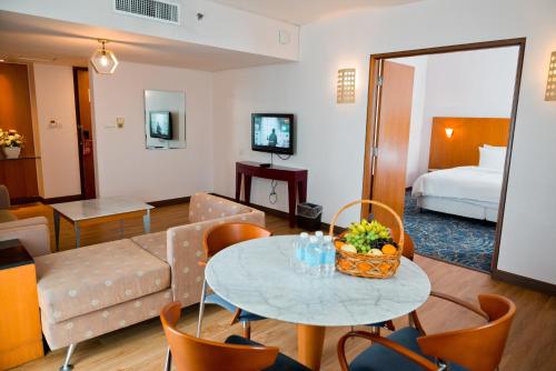 ビントゥルにあるパークシティ エバリー ホテル ビントゥルのテーブルとリビングルームが備わるホテルルームです。