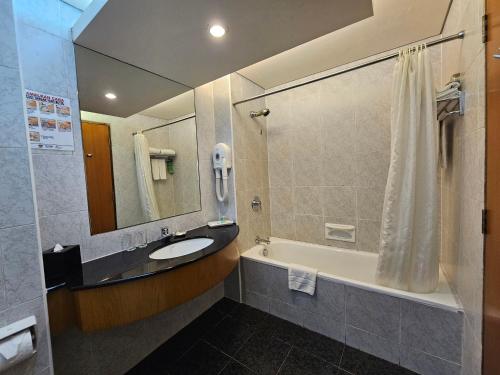 a bathroom with a sink and a tub and a shower at Parkcity Everly Hotel Bintulu in Bintulu