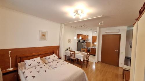 a bedroom with a bed and a table and a kitchen at Sunny Apartman in Siófok