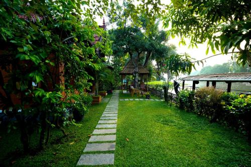 a garden with a walkway and a gazebo at Little Chembaka in Kumarakom