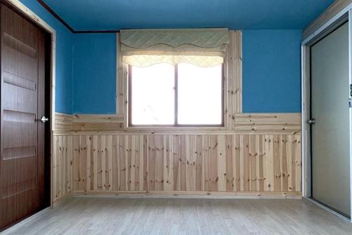 um quarto vazio com uma janela e paredes azuis em 바다와정원 Sea and Garden em Boryeong