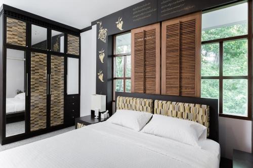 a bedroom with a large white bed and windows at Hide & Seek River Villa in Ban Wang Wa (1)