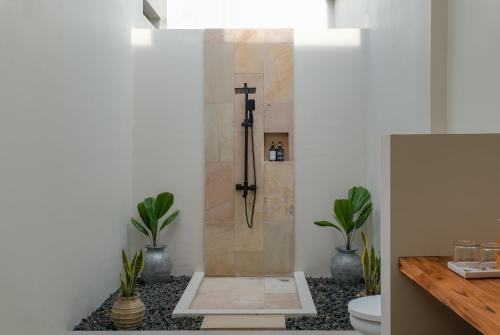 baño con ducha con una cruz en la pared en Lunna Villa, en Kuta Lombok
