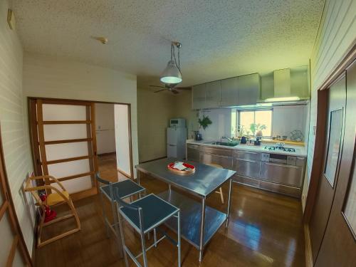 eine Küche mit einem Tisch und Stühlen sowie eine Küche mit einem Kühlschrank in der Unterkunft TSURUOKA GINZA 朙 sukima in Tsuruoka