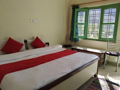 a bedroom with a bed with red and white sheets at Govind Bhanadhar in Rudraprayāg
