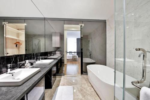 a bathroom with three sinks and a bath tub at The Platinum Serviced Suites by Faced in Kuala Lumpur