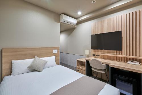 Hotel Villa Fontaine Tokyo-Jimbocho في طوكيو: غرفة نوم بسرير ومكتب وتلفزيون