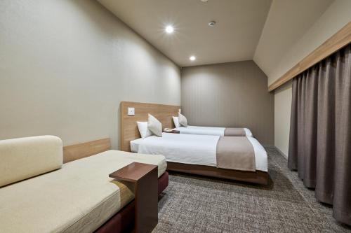 a hotel room with two beds and a couch at Hotel Villa Fontaine Tokyo-Jimbocho in Tokyo