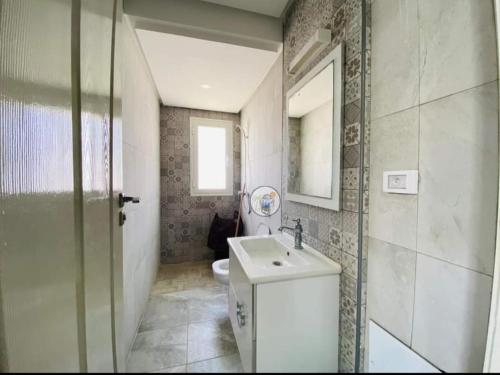W łazience znajduje się umywalka, toaleta i lustro. w obiekcie villa jassem w mieście Awlād ‘Umar