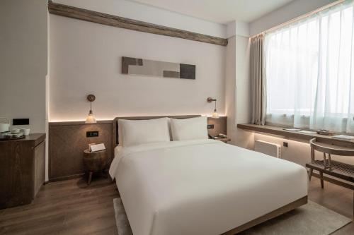 a bedroom with a large white bed and a desk at Sahe Hotel Shanghai World Expo in Shanghai