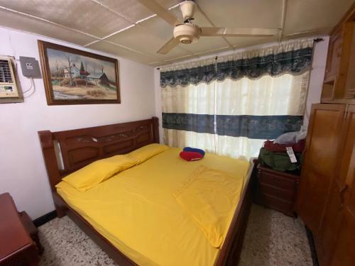 a bedroom with a yellow bed and a window at Casa Vecina Hostal in Santa Marta