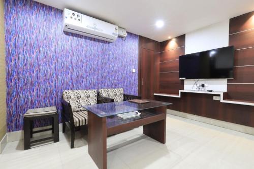 a room with a table and a tv and a couch at Hotel Rashmi Guwahati in Guwahati