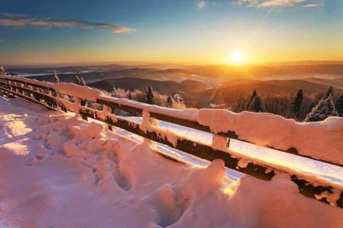a train covered in snow with the sunset in the background at Krynicka Koliba na Jaworzynie Krynickiej in Krynica Zdrój