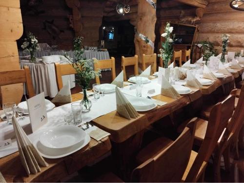 einen langen Holztisch mit weißen Tellern und Servietten in der Unterkunft Krynicka Koliba na Jaworzynie Krynickiej in Krynica-Zdrój