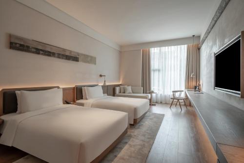 a hotel room with two beds and a flat screen tv at Sahe Hotel Shanghai World Expo in Shanghai