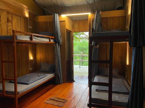 Pokój z 3 łóżkami piętrowymi i drzwiami w obiekcie Hahaland w mieście Phong Nha