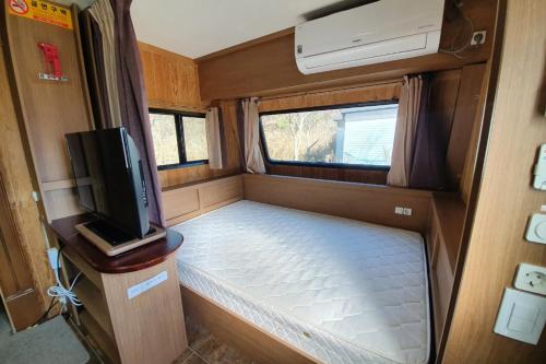 Byeonsan Auto Camping في بوان: غرفة صغيرة فيها سرير وتلفزيون