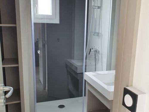 a bathroom with a glass shower and a sink at Chalet Confort 2 Chambres avec Piscine Chauffée et Climatisation en Bretagne Sud - FR-1-783-19 in Marzan