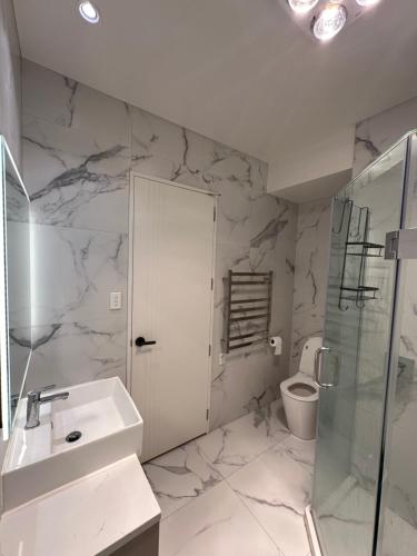 a white bathroom with a sink and a toilet at 2 Bedrooms in Flat Bush in Auckland