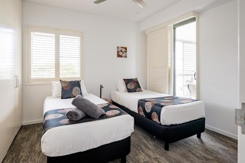 two beds in a room with two windows at Serenity Neptuna - 3brm luxury at Darwin Waterfront in Darwin