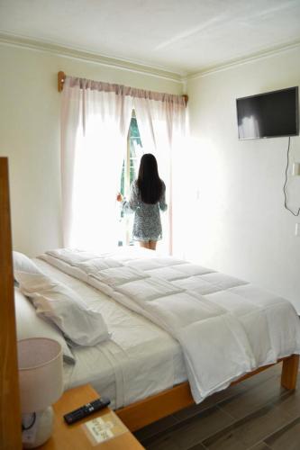 a woman looking out the window of a bedroom at Hotel BEMAR in La Trinitaria