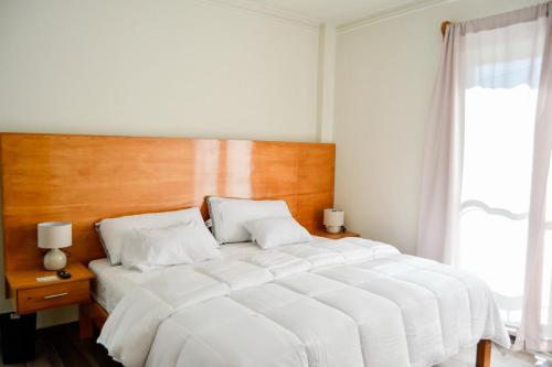 a bedroom with a large white bed with a wooden headboard at Hotel BEMAR in La Trinitaria