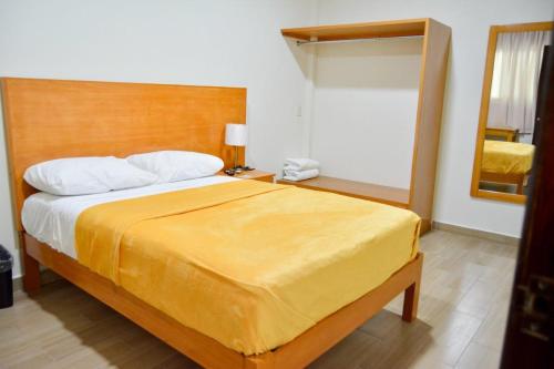 a bedroom with a large bed with a yellow blanket at Hotel BEMAR in La Trinitaria