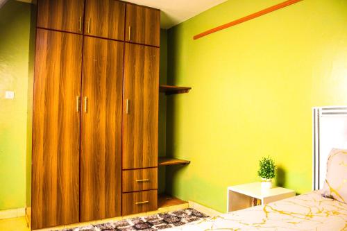 a bedroom with a large wooden cabinet next to a bed at S & A APARTMENTS in Thika