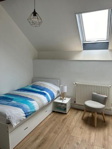 um quarto com uma cama, uma cadeira e uma janela em Spacieux duplex à Folschviller 