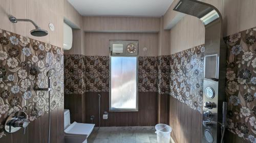 een badkamer met een douche, een toilet en een raam bij El Cielo, B&B in Shimla